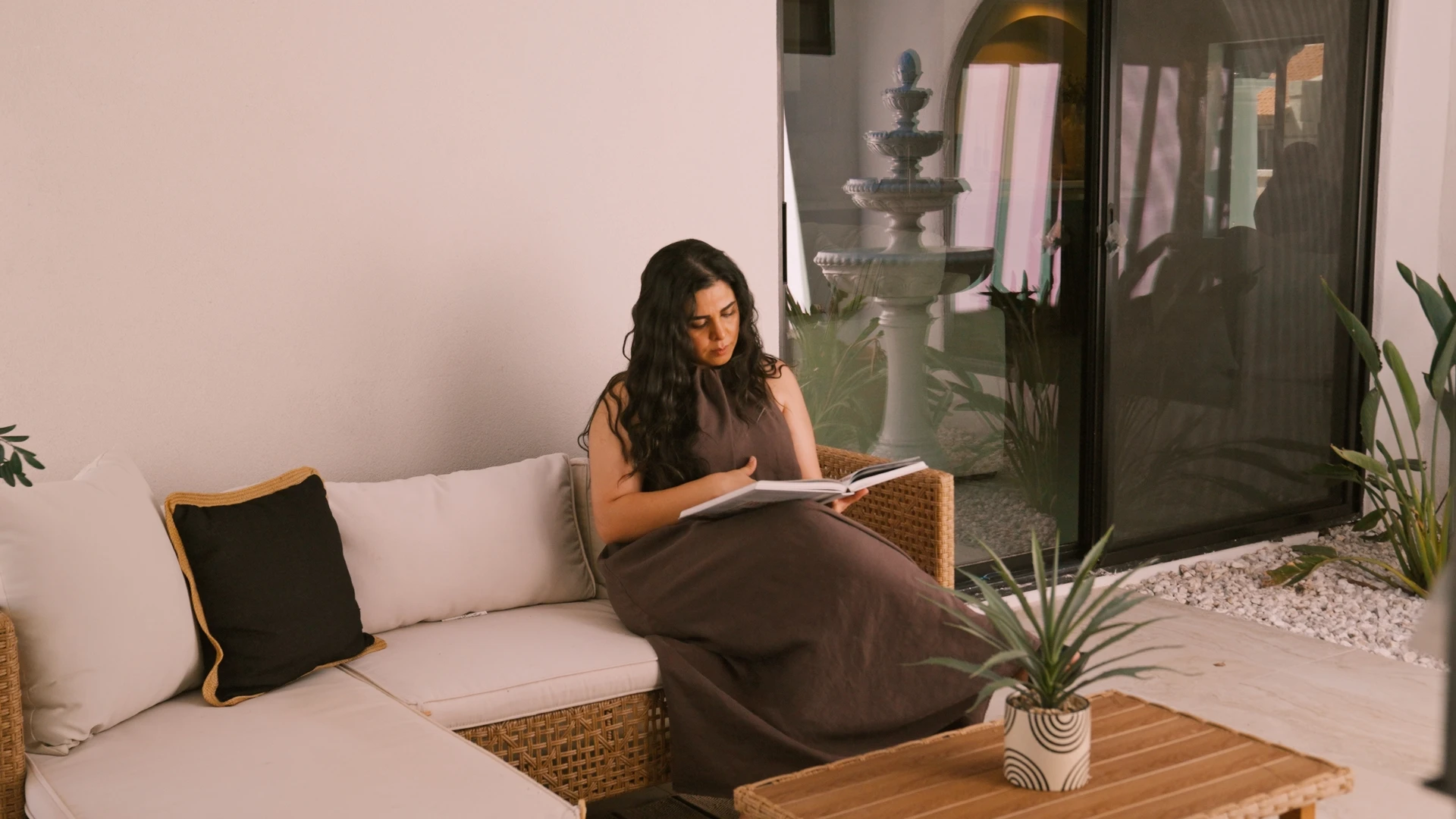 Woman reading on a sofa beside the courtyard